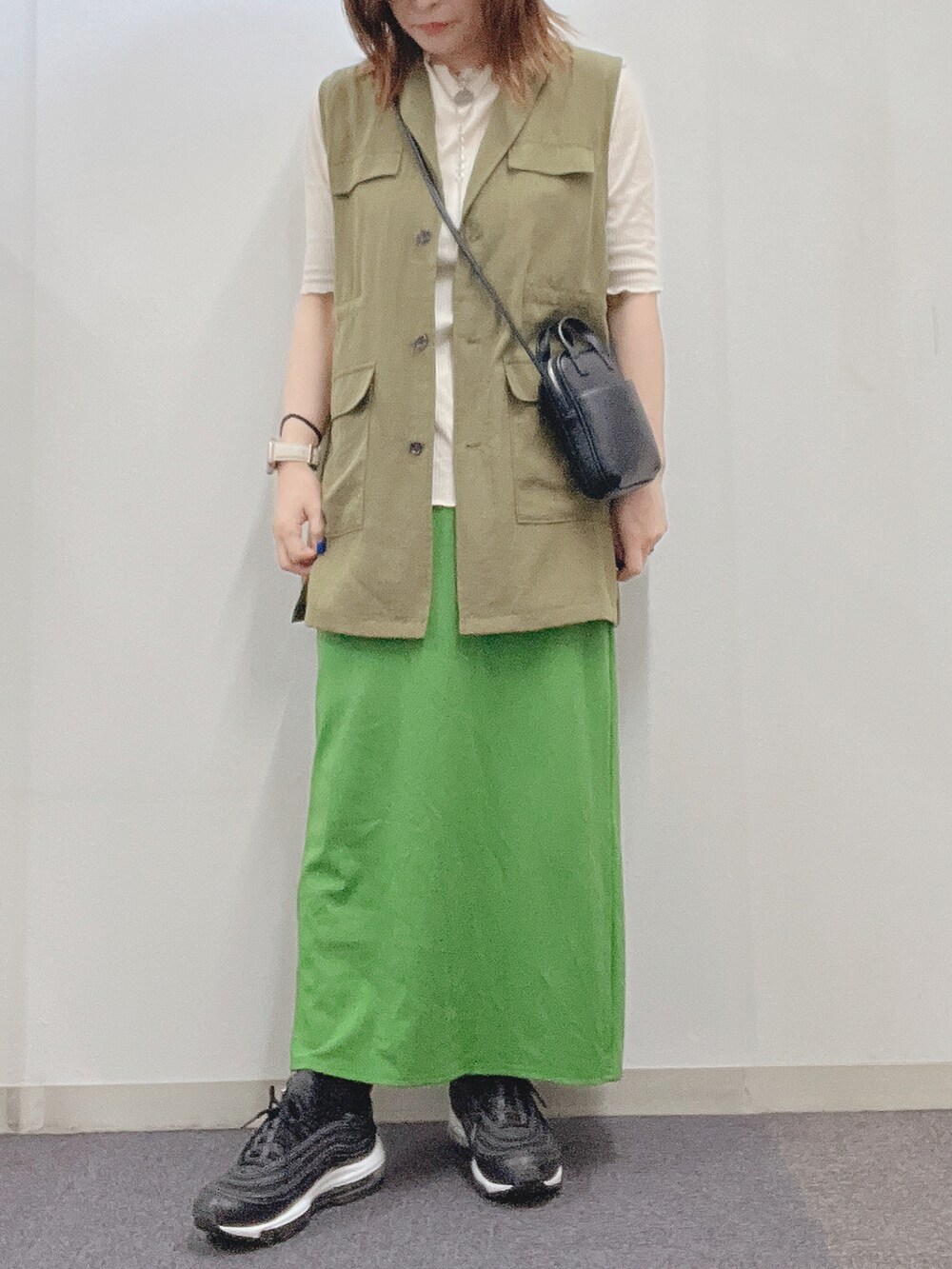 グリーン系のベスト、グリーン系のスカート、ホワイト系のTシャツ/カットソーを着用したレディースの春コーディネートの2枚目の写真