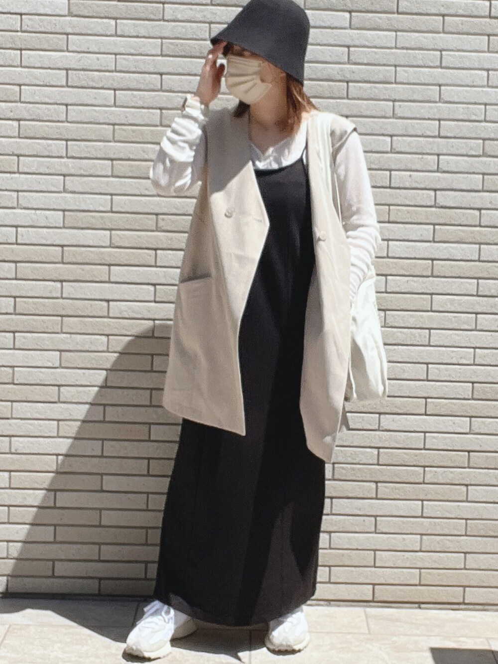 グレー系のベスト、ブラック系のワンピース、ホワイト系のTシャツ/カットソーを着用したレディースの春コーディネートの2枚目の写真