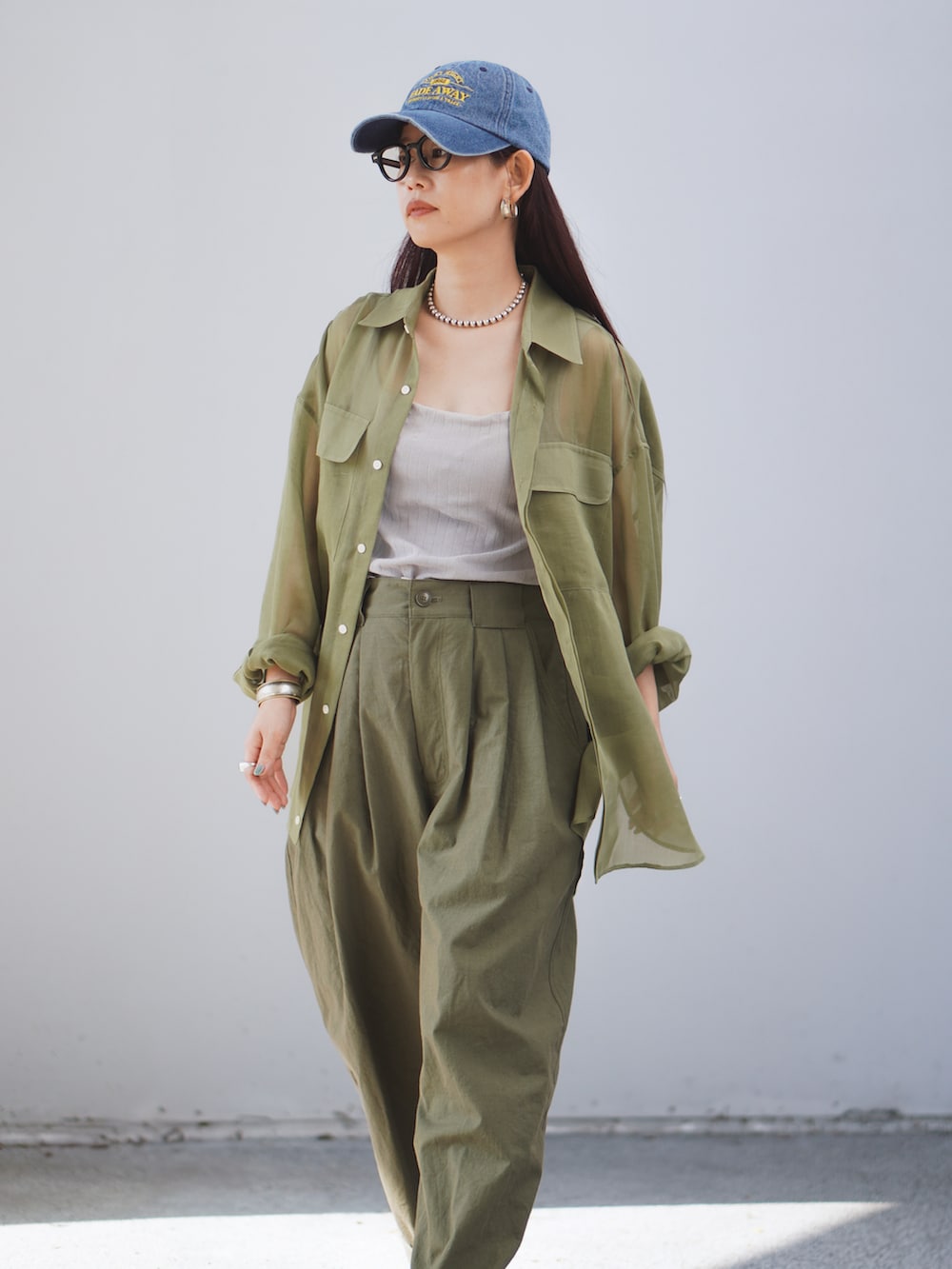 グリーン系のパンツ、グリーン系のシャツ/ブラウス、ブラック系のサンダルを着用したレディースの春コーディネートの3枚目の写真