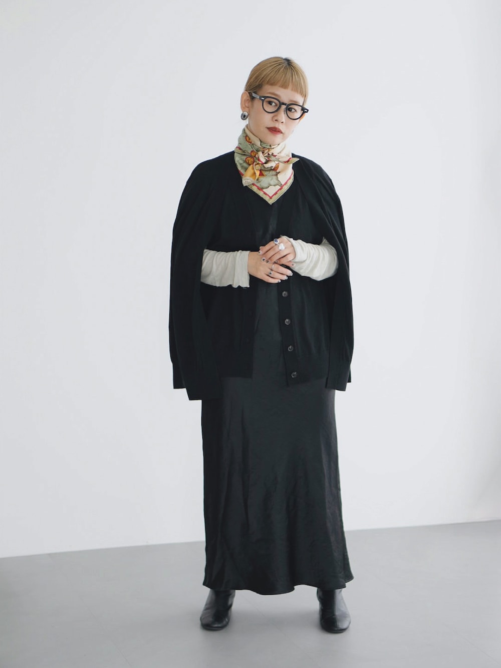 ブラック系のワンピース、ブラック系のカーディガン/ボレロ、ブラック系のブーツを着用したレディースの秋コーディネートの2枚目の写真