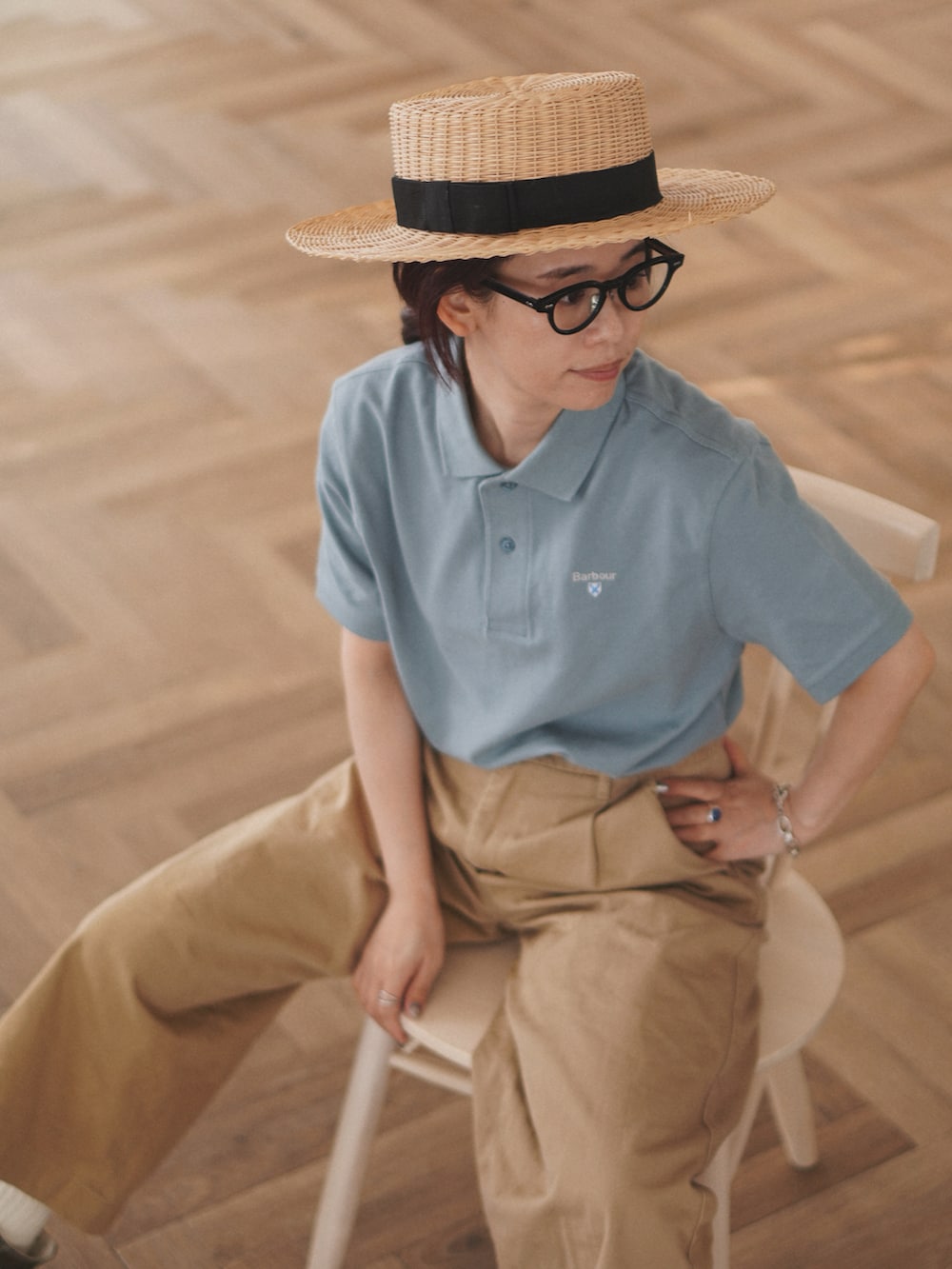 ブルー系のポロシャツ、ベージュ系のチノパンツ、ベージュ系のカーディガン/ボレロを着用したレディースの春コーディネートの2枚目の写真