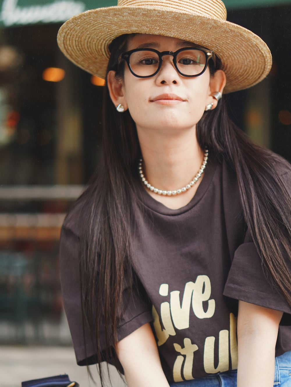 ブルー系のデニムパンツ、ブラック系のショルダーバッグ、ブラウン系のTシャツ/カットソーを着用したレディースの夏コーディネートの2枚目の写真