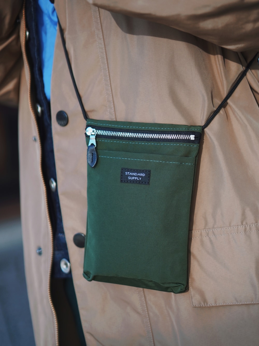 ベージュ系のその他アウター、グリーン系のショルダーバッグ、グリーン系のスカートを着用したレディースの冬コーディネートの2枚目の写真