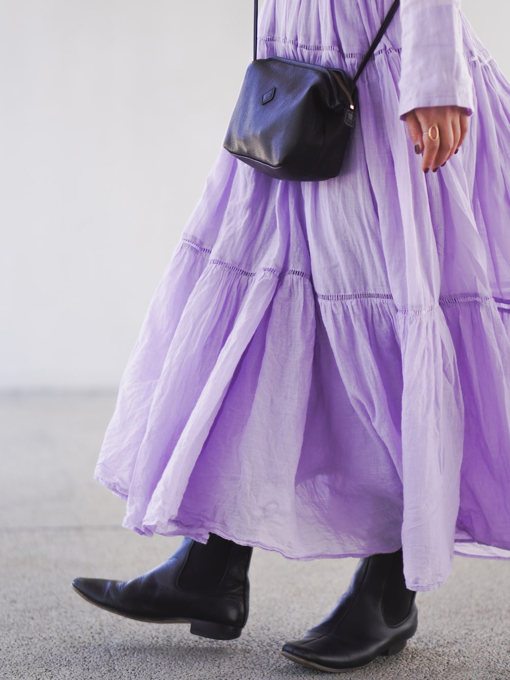 パープル系のワンピース、ブラック系のショルダーバッグ、ブラック系のブーツを着用したレディースの冬コーディネートの2枚目の写真