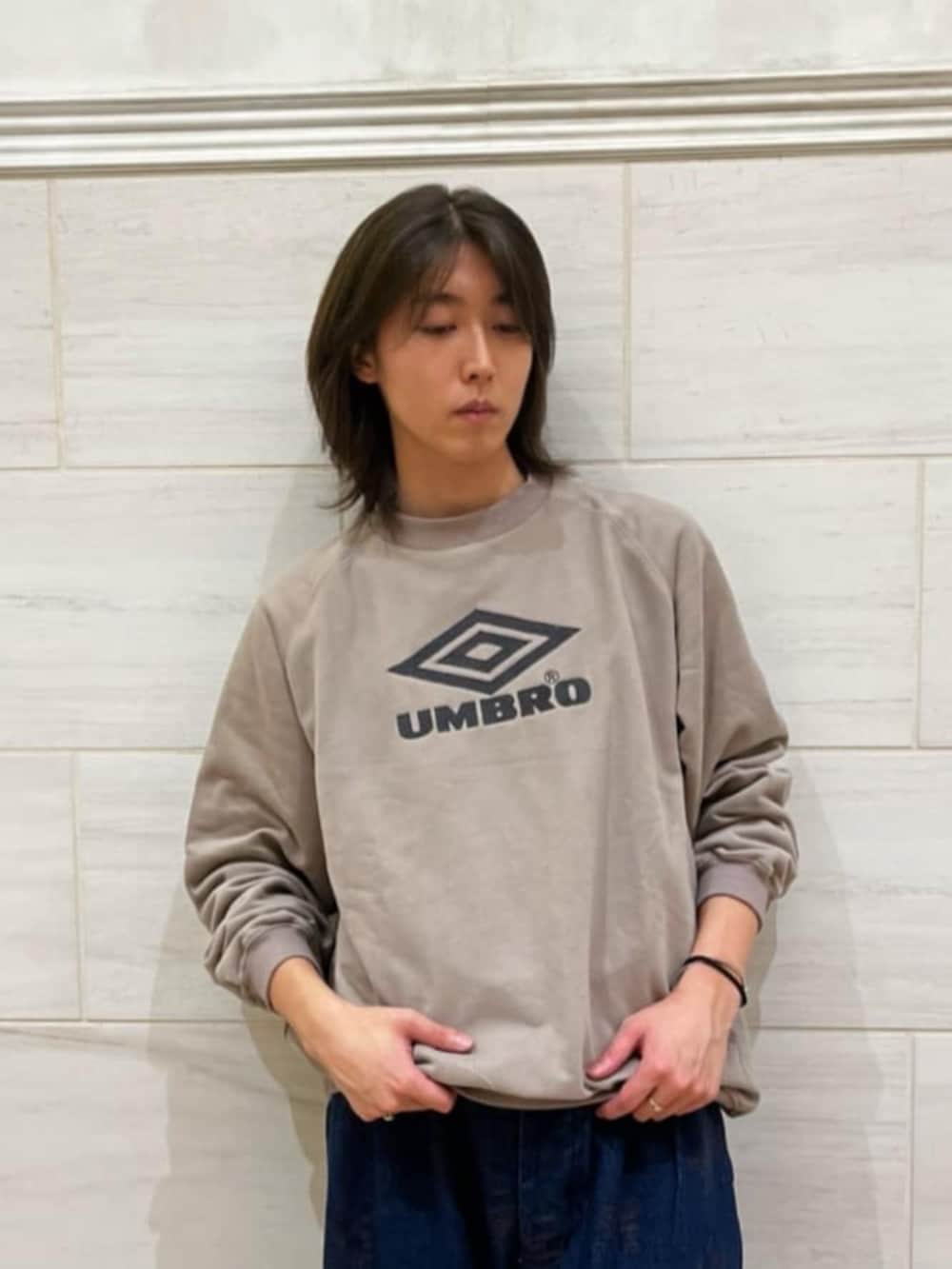 ベージュ系のスウェット、ブルー系のデニムパンツ、ブラウン系のスニーカーを着用したメンズの秋コーディネートの2枚目の写真