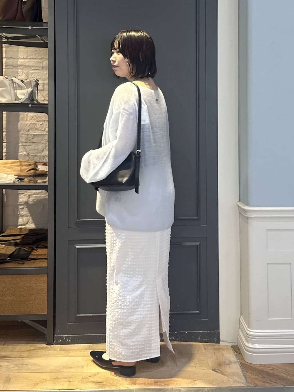 ブラック系のショルダーバッグ、ブラック系のパンプス、ホワイト系のスカートを着用したレディースの秋コーディネートの2枚目の写真