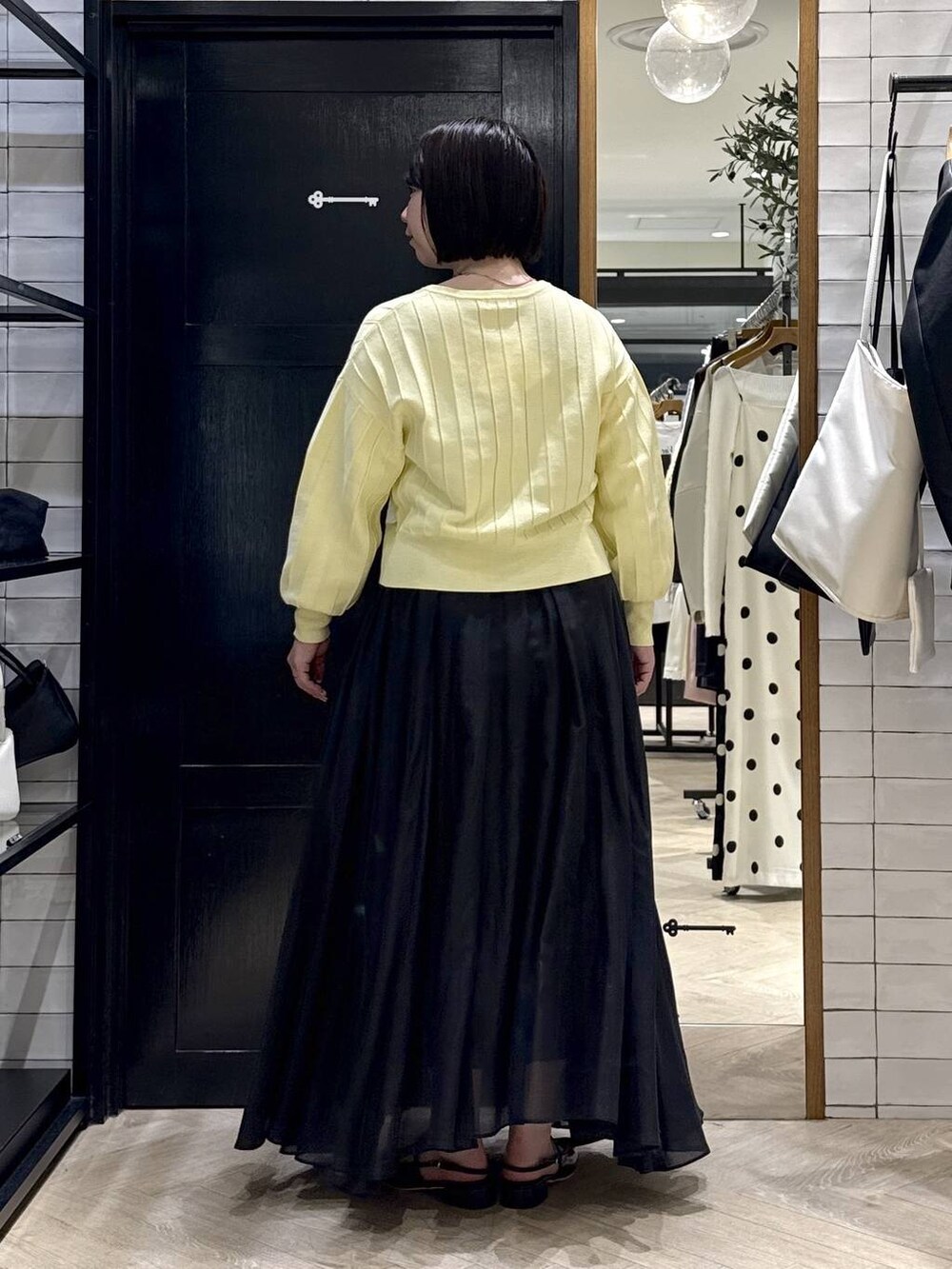 イエロー系のカーディガン/ボレロ、ブラック系のスカート、ブラック系のパンプスを着用したレディースの春コーディネートの3枚目の写真