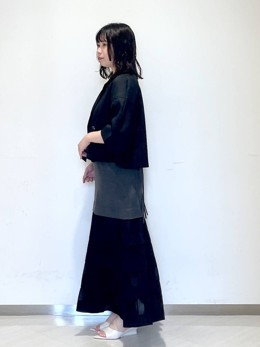 ホワイト系のサンダル、グレー系のワンピース、ブラック系のテーラードジャケットを着用したレディースの夏コーディネートの2枚目の写真