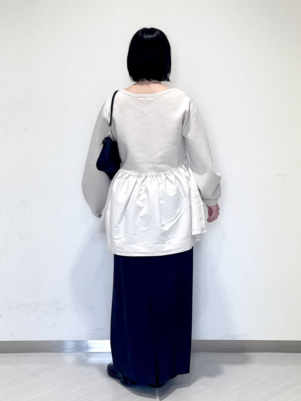 ブラック系のショルダーバッグ、グレー系のスカート、ブラック系のブーツを着用したレディースの秋コーディネートの3枚目の写真