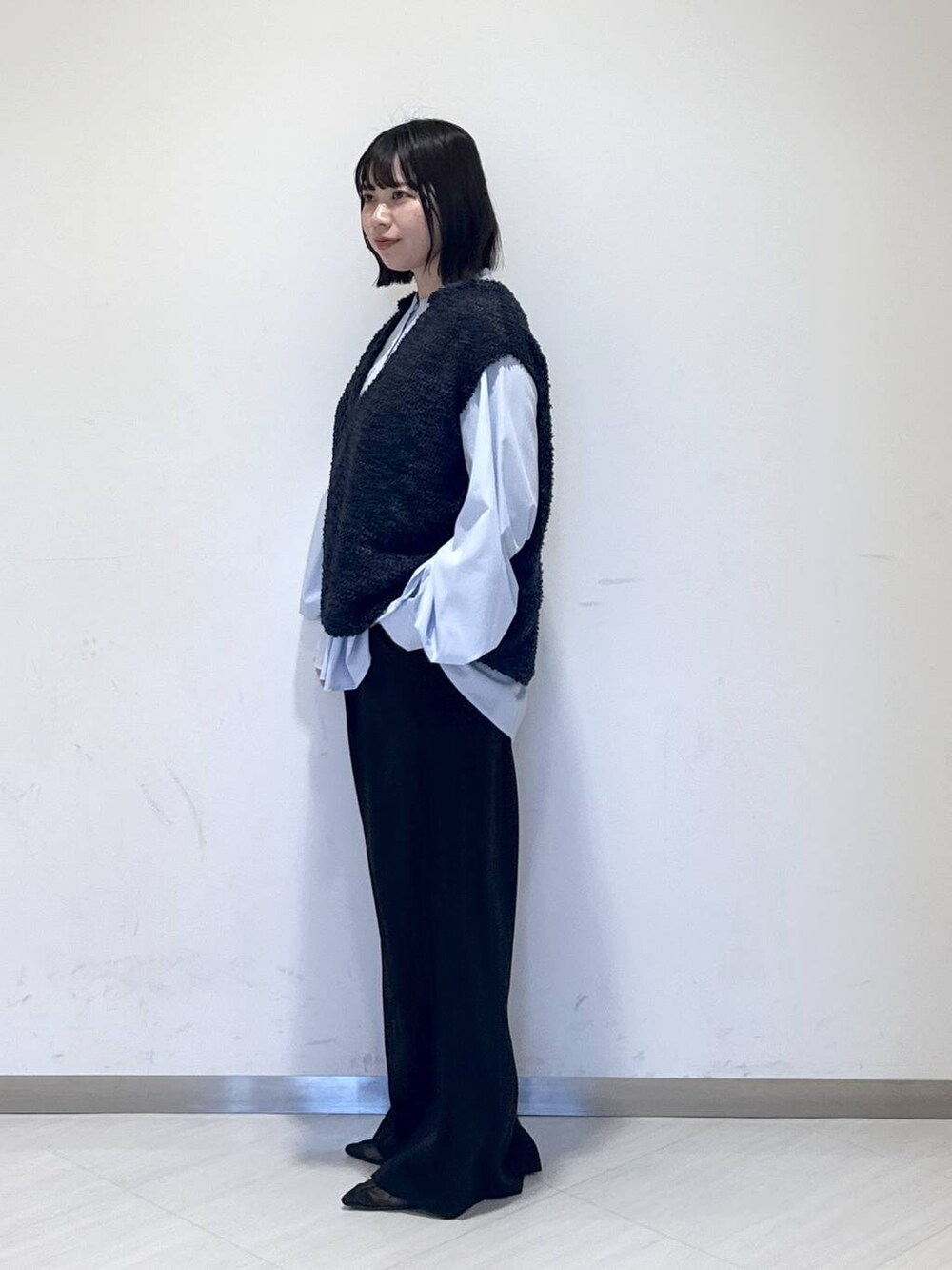 ブラック系のスラックス、ブルー系のTシャツ/カットソー、ブルー系のベストを着用したレディースの冬コーディネートの2枚目の写真