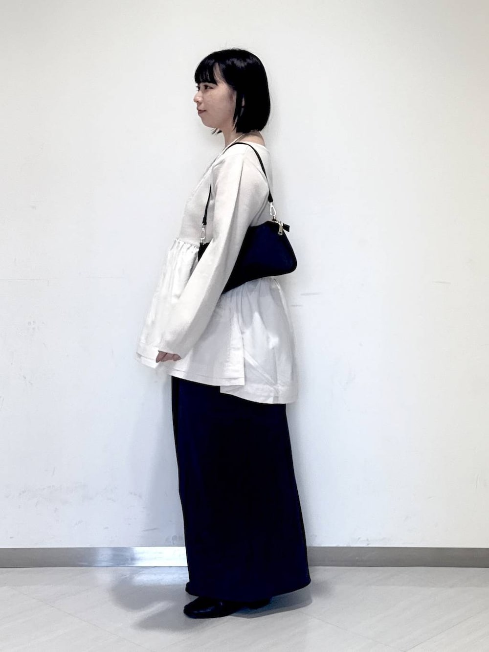 ブラック系のショルダーバッグ、グレー系のスカート、ブラック系のブーツを着用したレディースの秋コーディネートの2枚目の写真