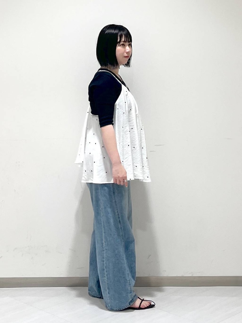 ブルー系のデニムパンツ、ブラック系のサンダル、ブラック系のTシャツ/カットソーを着用したレディースの春コーディネートの2枚目の写真