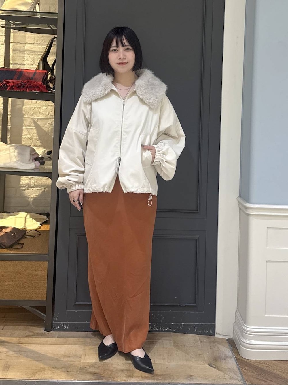 ブラック系のパンプス、ホワイト系のブルゾン、オレンジ系のスカートを着用したレディースの秋コーディネートの5枚目の写真