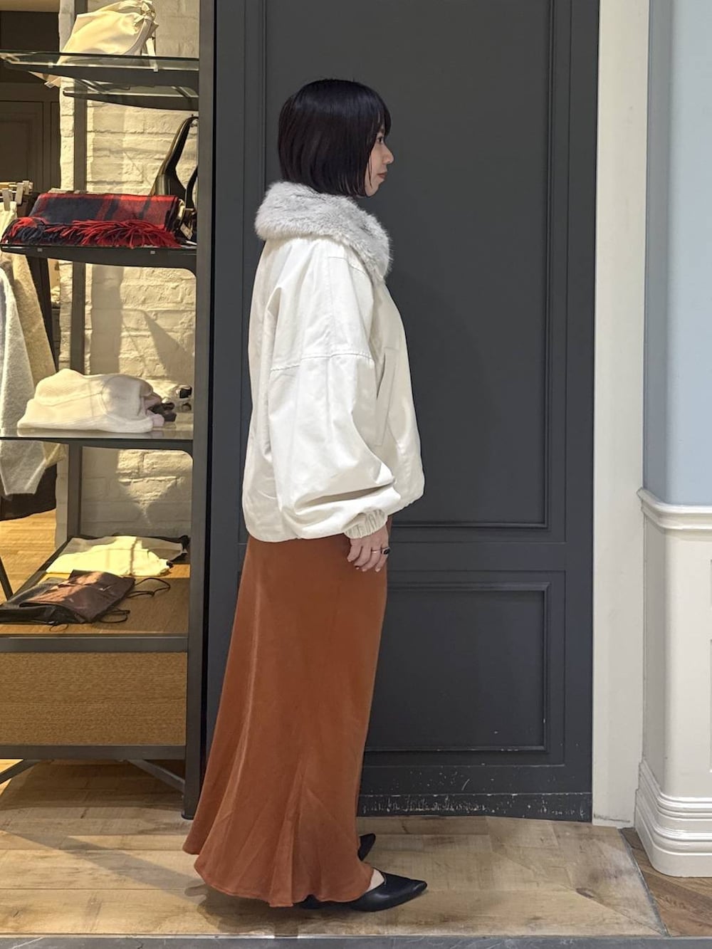 ブラック系のパンプス、ホワイト系のブルゾン、オレンジ系のスカートを着用したレディースの秋コーディネートの3枚目の写真