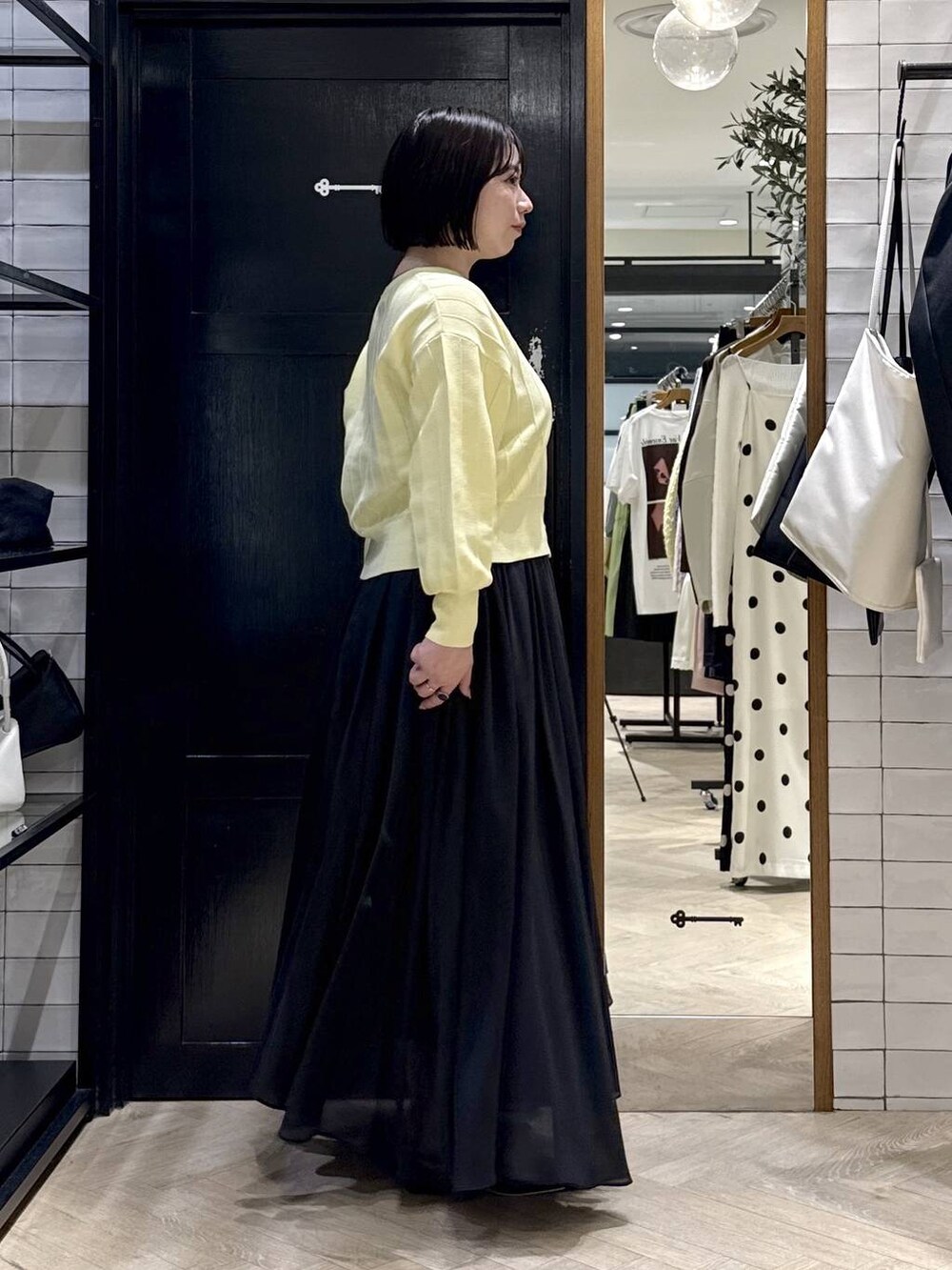 イエロー系のカーディガン/ボレロ、ブラック系のスカート、ブラック系のパンプスを着用したレディースの春コーディネートの2枚目の写真