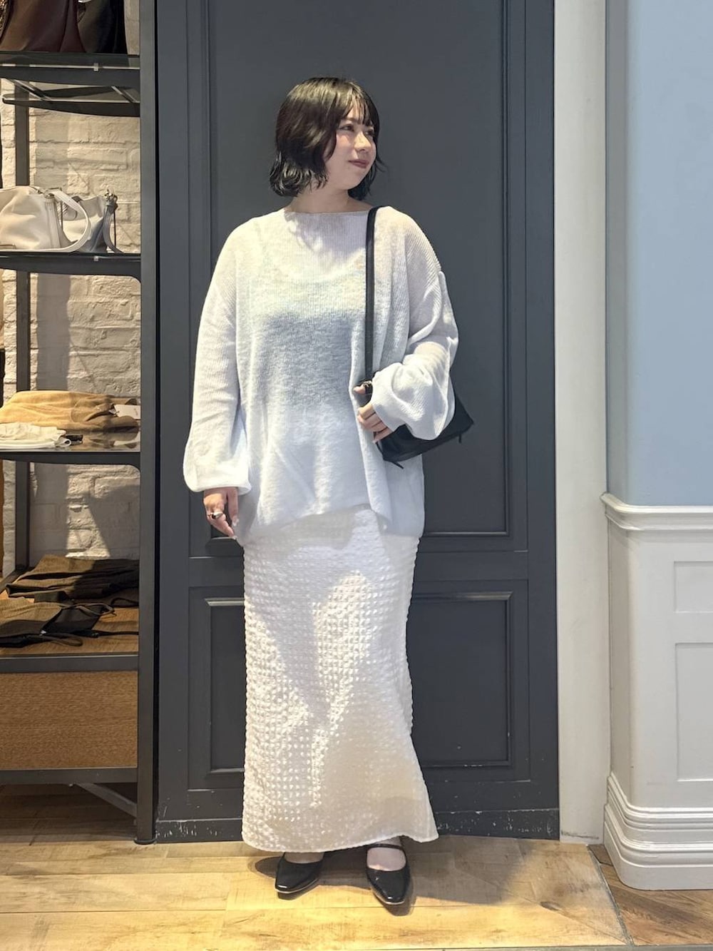 ブラック系のショルダーバッグ、ブラック系のパンプス、ホワイト系のスカートを着用したレディースの秋コーディネートの4枚目の写真