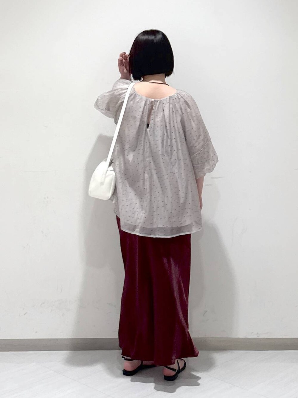 ブラック系のサンダル、ホワイト系のハンドバッグ、レッド系のスカートを着用したレディースの夏コーディネートの3枚目の写真