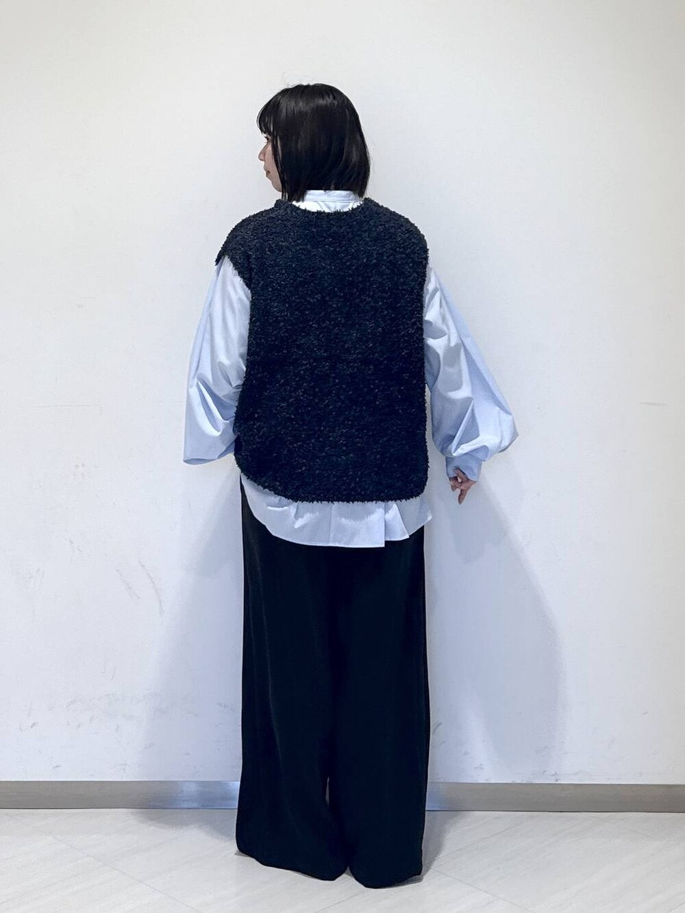 ブラック系のスラックス、ブルー系のTシャツ/カットソー、ブルー系のベストを着用したレディースの冬コーディネートの3枚目の写真