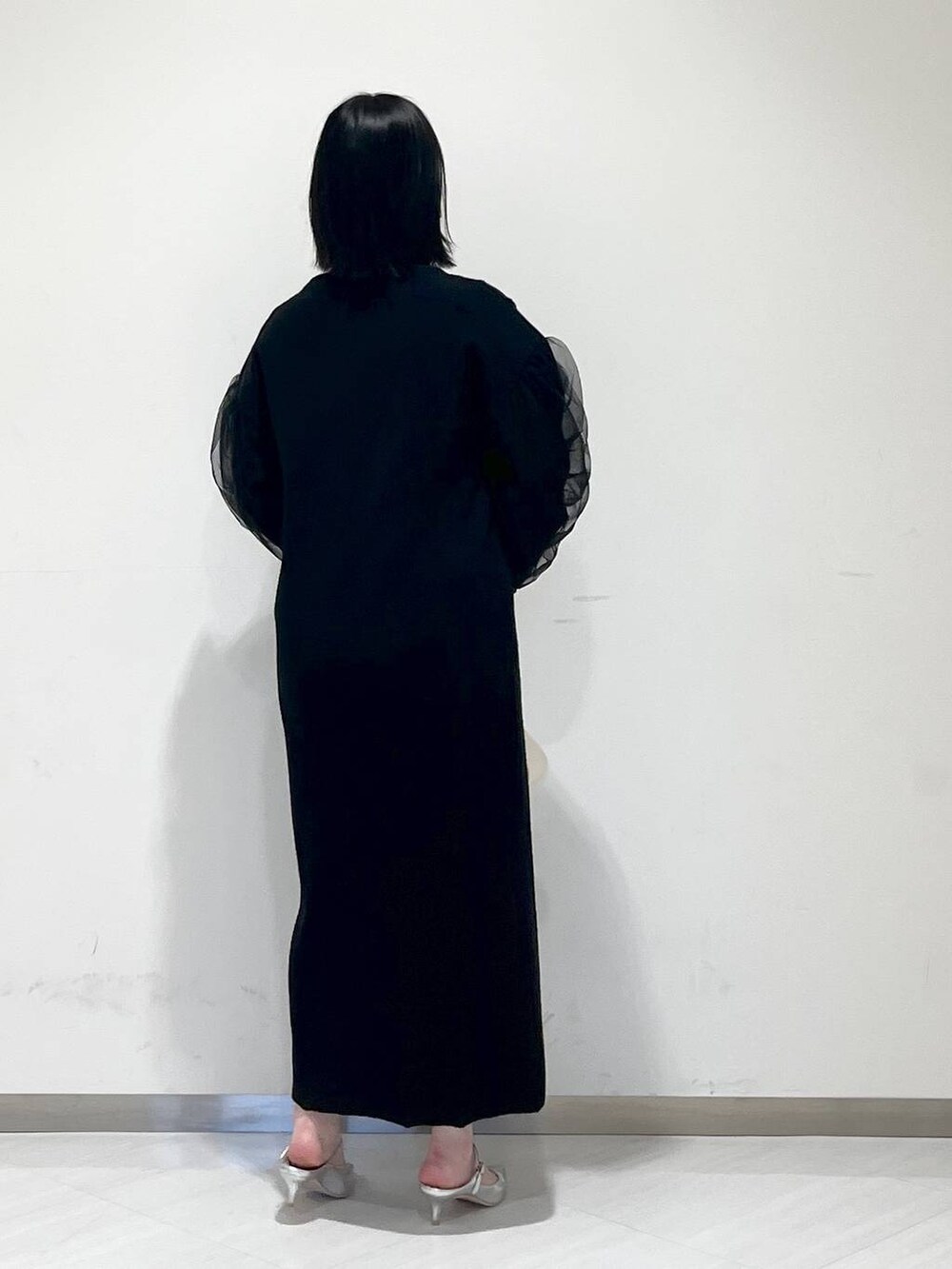 シルバー系のサンダル、ホワイト系のショルダーバッグ、ブラック系のワンピースを着用したレディースの冬コーディネートの3枚目の写真