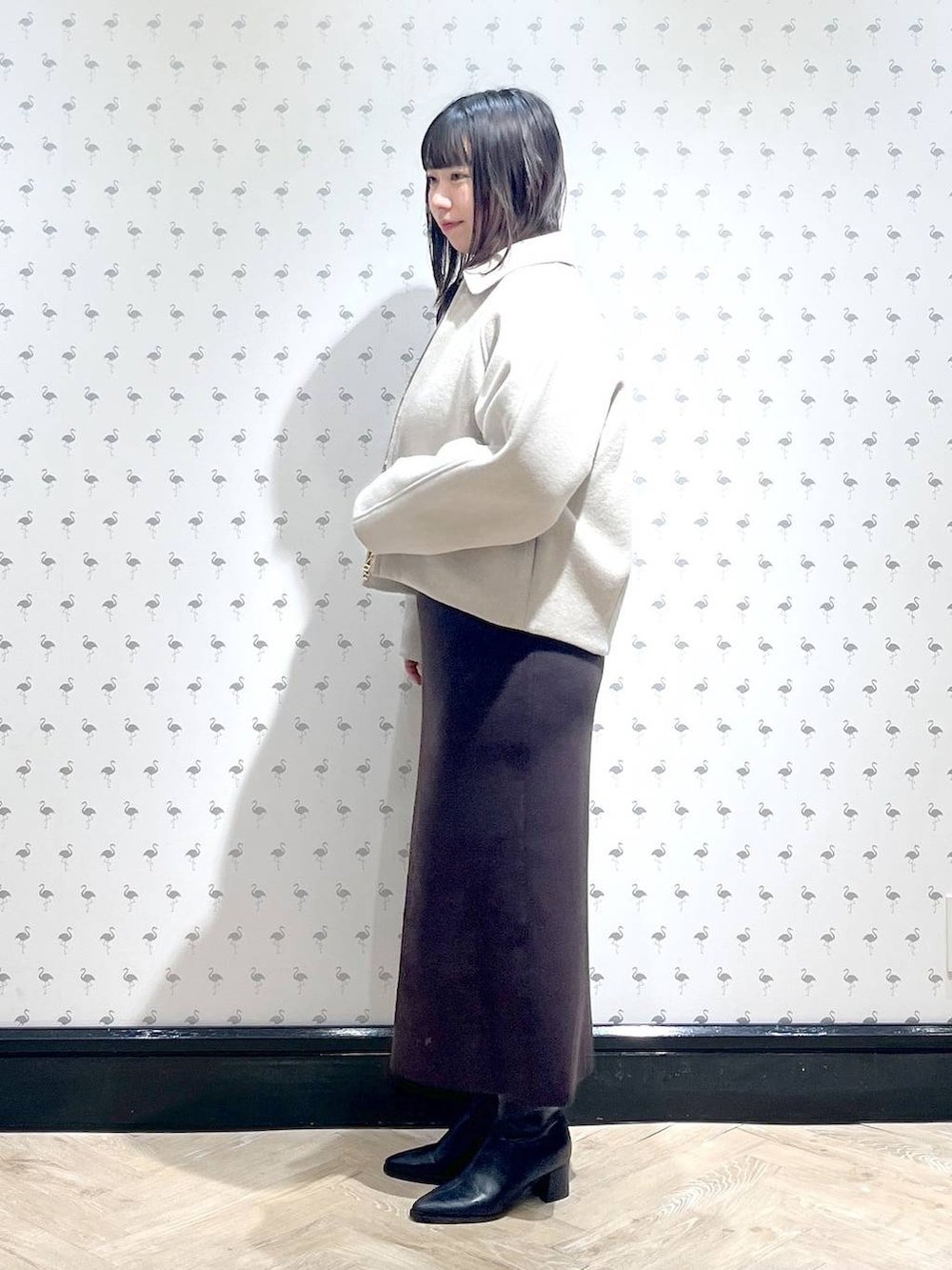 ベージュ系のブルゾン、ブラウン系のワンピース、ブラック系のブーツを着用したレディースの冬コーディネートの2枚目の写真