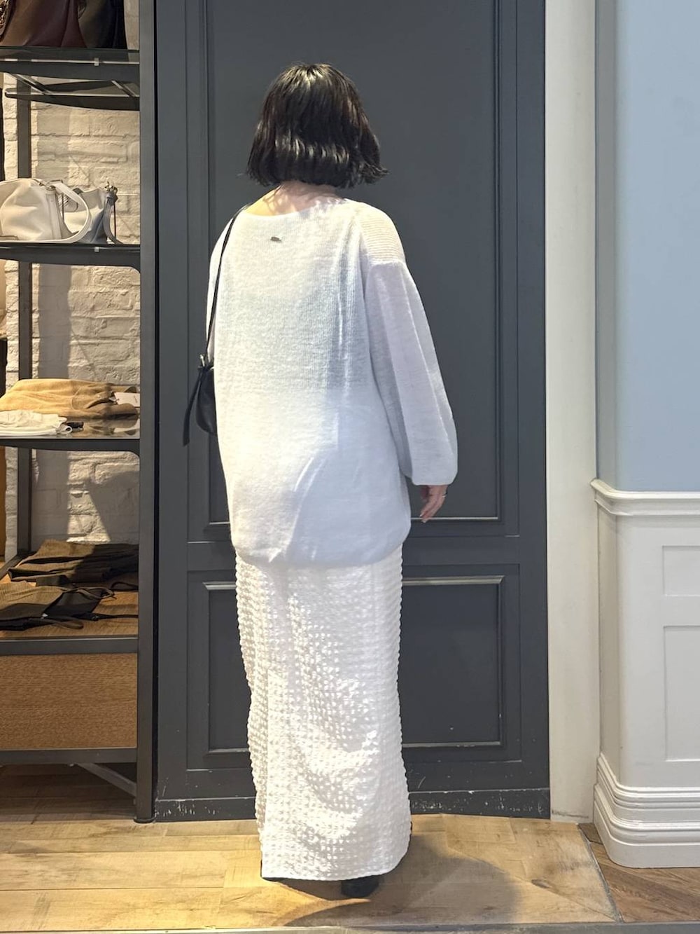 ブラック系のショルダーバッグ、ブラック系のパンプス、ホワイト系のスカートを着用したレディースの秋コーディネートの3枚目の写真