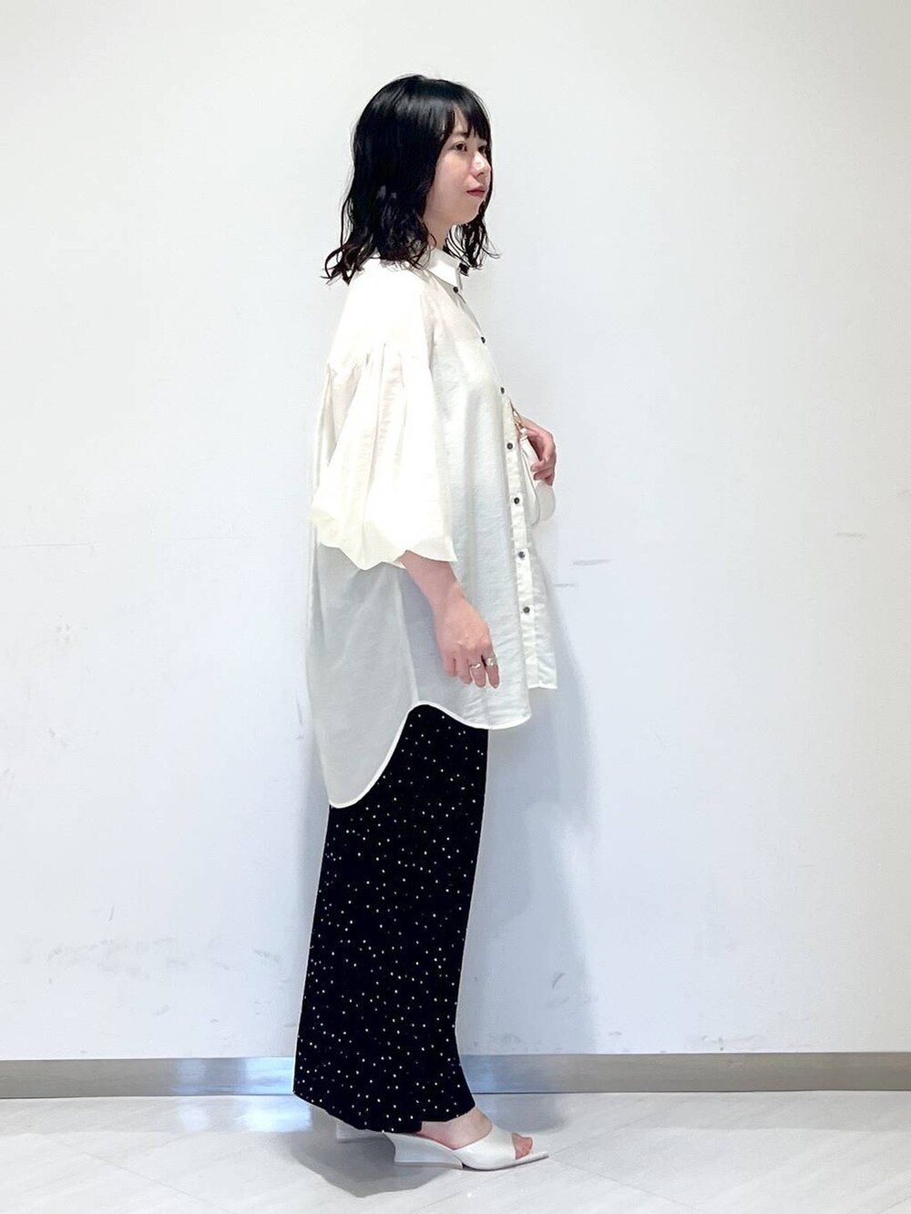 ホワイト系のシャツ/ブラウス、ホワイト系のショルダーバッグ、ブラック系のスカートを着用したレディースの夏コーディネートの2枚目の写真