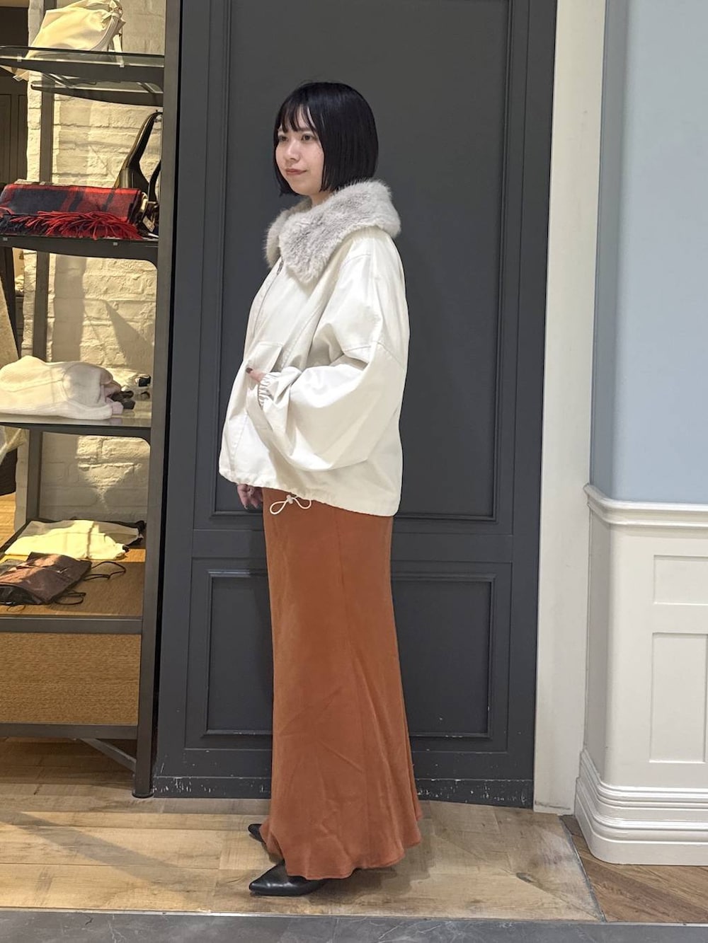 ブラック系のパンプス、ホワイト系のブルゾン、オレンジ系のスカートを着用したレディースの秋コーディネートの2枚目の写真