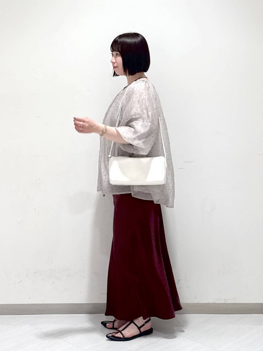 ブラック系のサンダル、ホワイト系のハンドバッグ、レッド系のスカートを着用したレディースの夏コーディネートの2枚目の写真