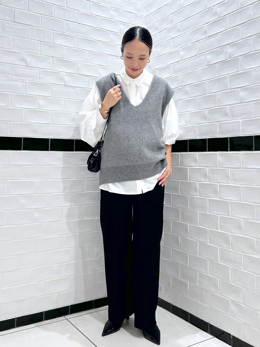 ブラック系のスラックス、グレー系のベスト、ホワイト系のシャツ/ブラウスを着用したレディースの秋コーディネートの3枚目の写真