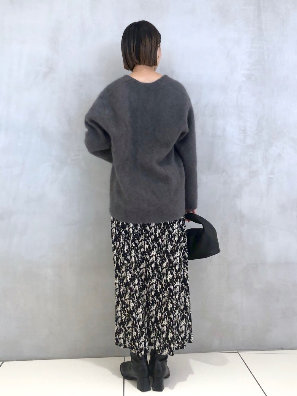 グレー系のニット/セーター、ブラック系のハンドバッグ、グレー系のスカートを着用したレディースの秋コーディネートの3枚目の写真