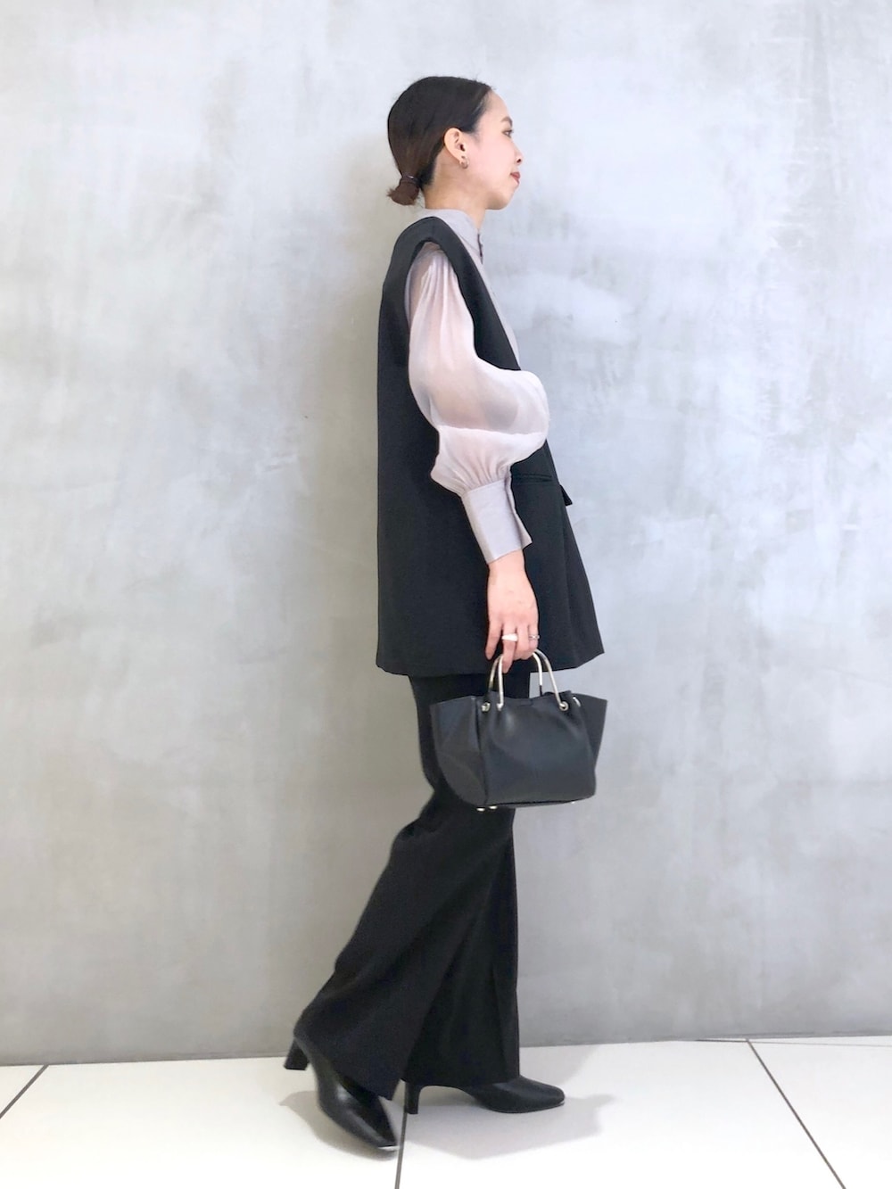 ブラック系のスーツセット、ブラック系のショルダーバッグ、ブラック系のパンプスを着用したレディースの冬コーディネートの2枚目の写真
