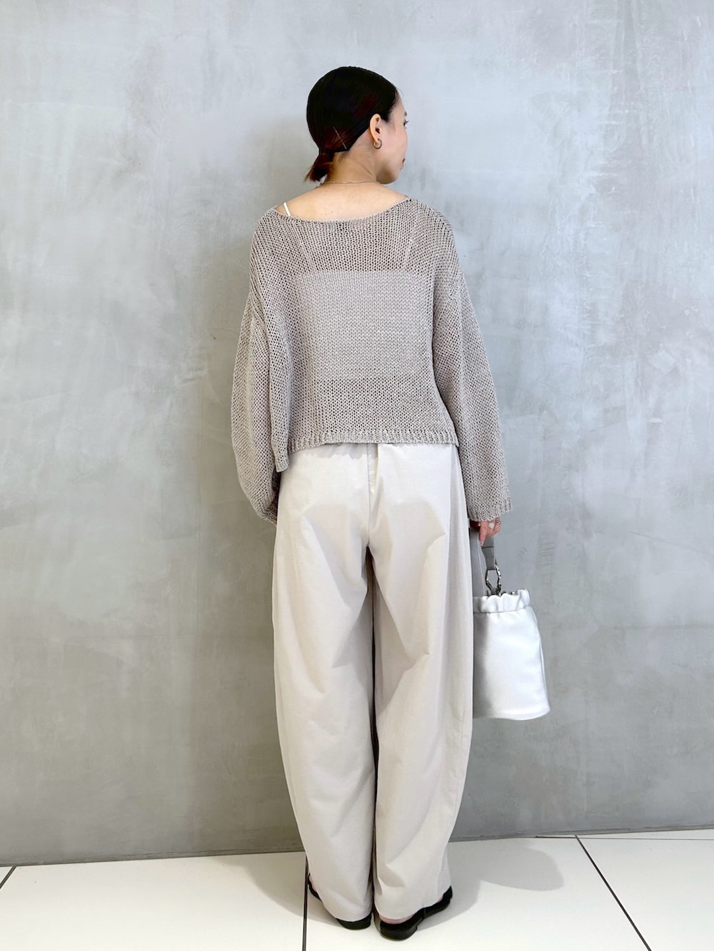 グレー系のその他パンツ、シルバー系のショルダーバッグ、グレー系のニット/セーターを着用したレディースの夏コーディネートの2枚目の写真