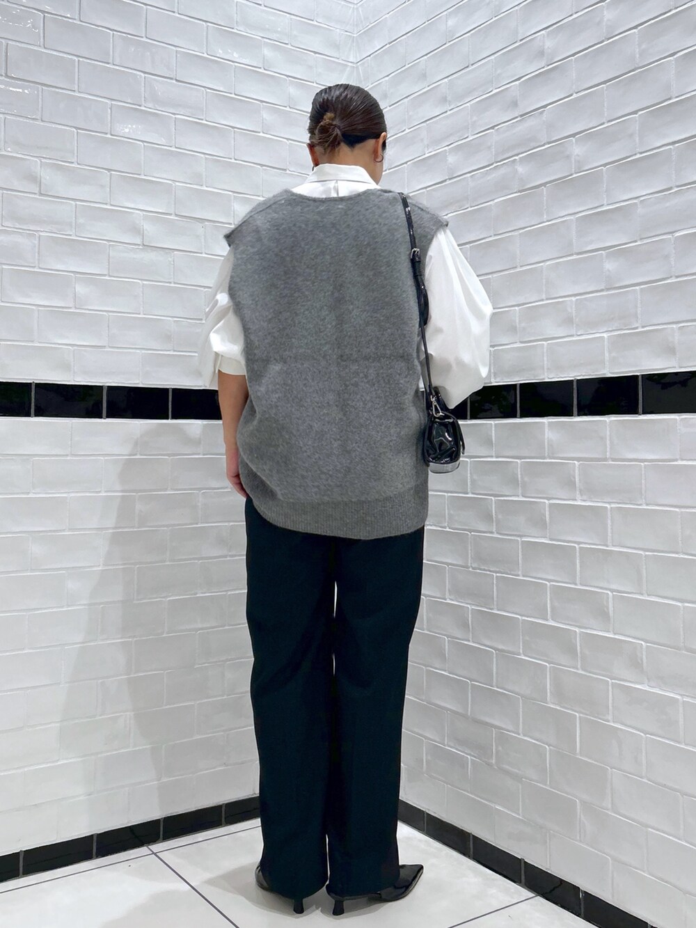 ブラック系のスラックス、グレー系のベスト、ホワイト系のシャツ/ブラウスを着用したレディースの秋コーディネートの2枚目の写真