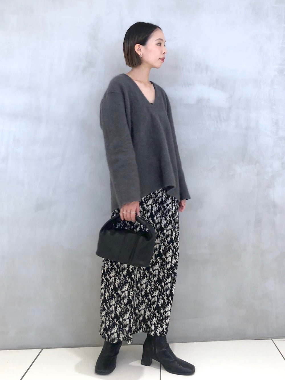 グレー系のニット/セーター、ブラック系のハンドバッグ、グレー系のスカートを着用したレディースの秋コーディネートの2枚目の写真