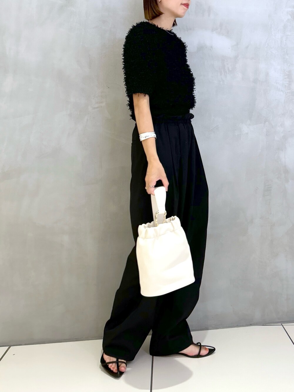 ブラック系のその他パンツ、ブラック系のニット/セーター、ホワイト系のショルダーバッグを着用したレディースの夏コーディネートの3枚目の写真