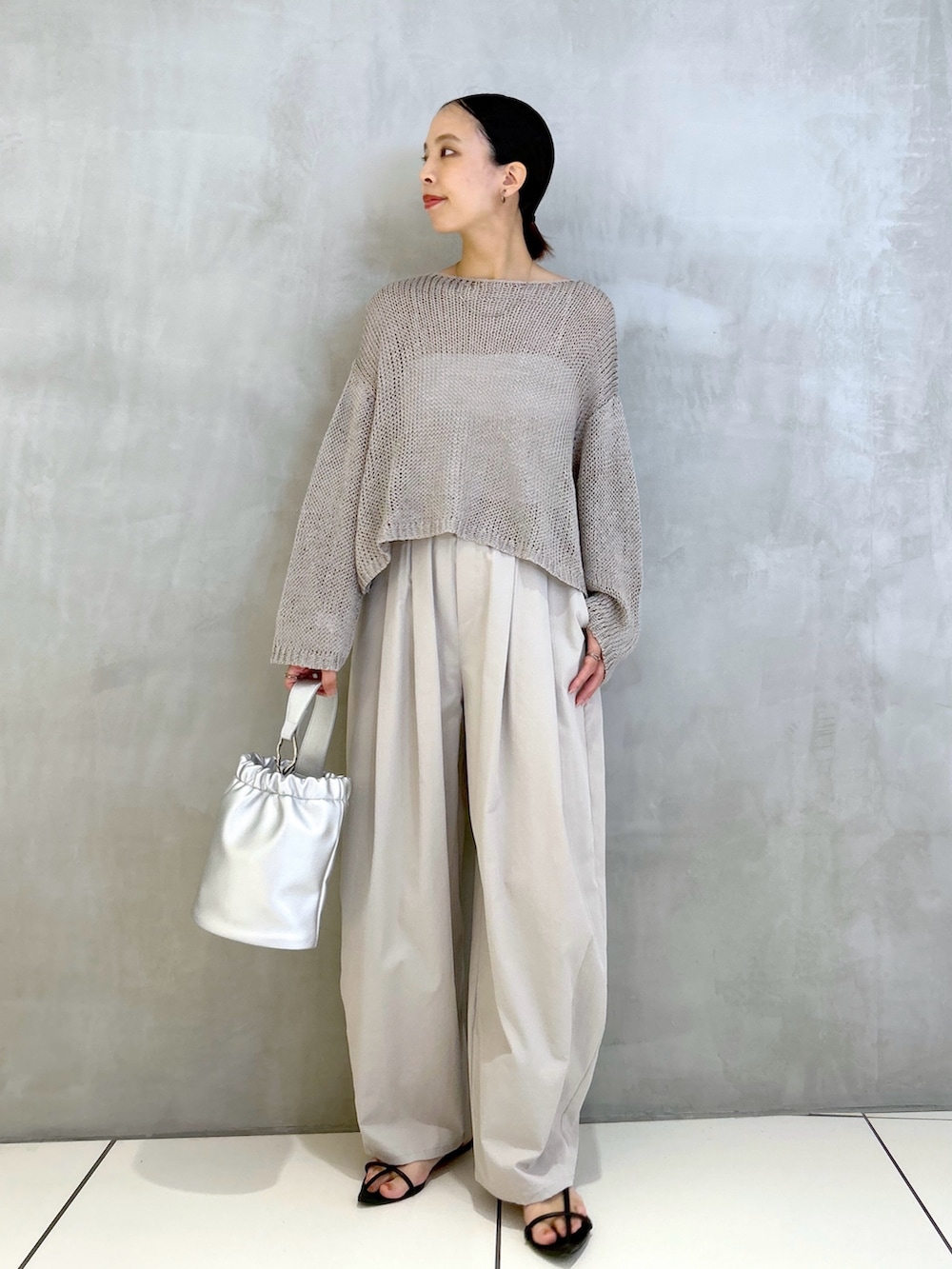 グレー系のその他パンツ、シルバー系のショルダーバッグ、グレー系のニット/セーターを着用したレディースの夏コーディネートの3枚目の写真