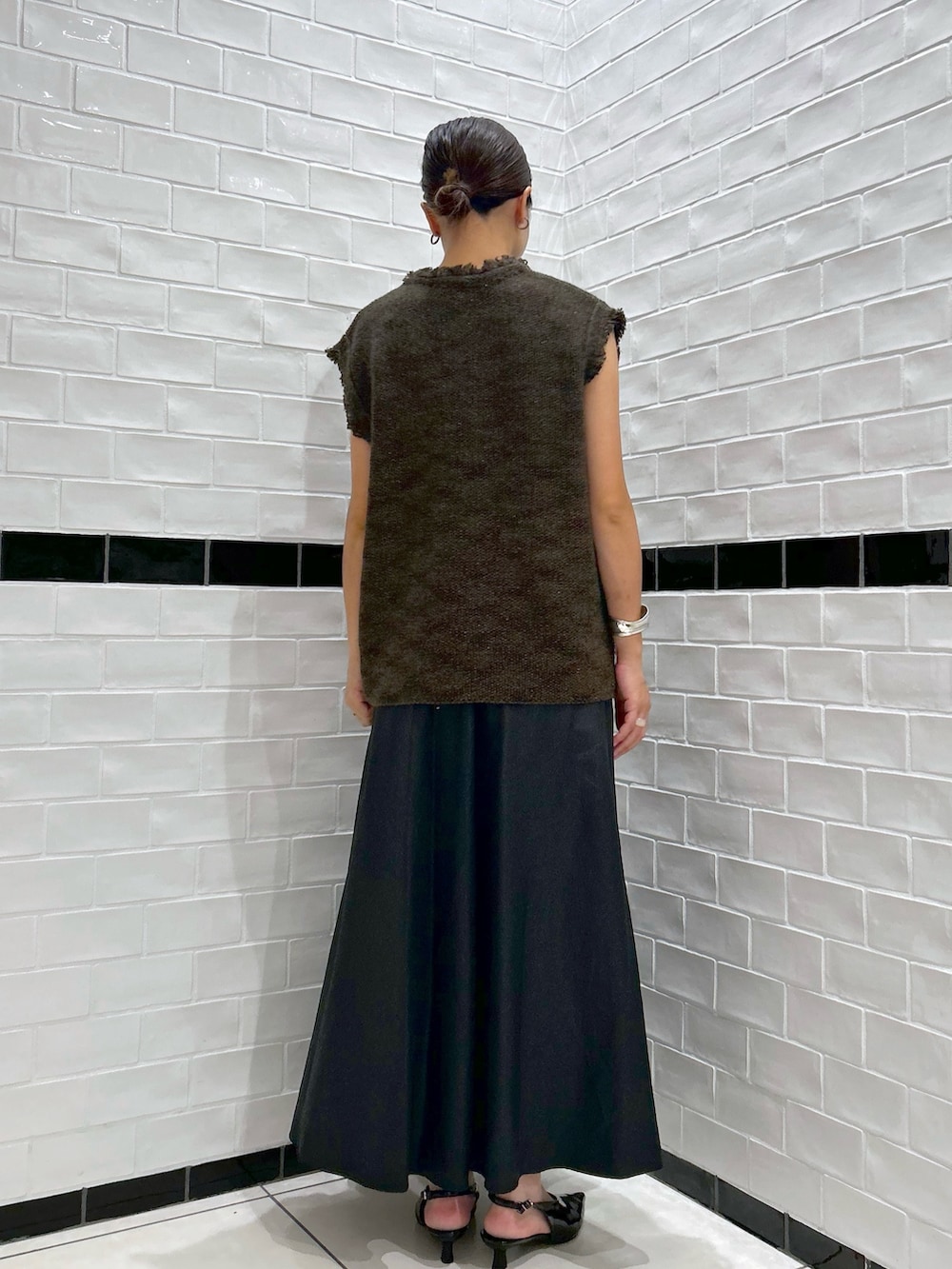 ブラウン系のベスト、ブラック系のスカート、ブラック系のパンプスを着用したレディースの秋コーディネートの2枚目の写真