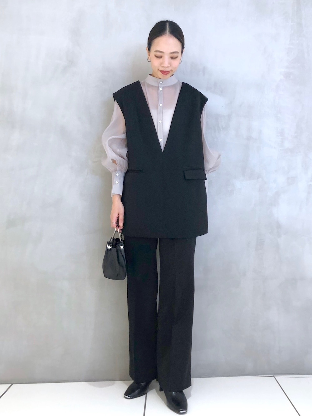 ブラック系のスーツセット、ブラック系のショルダーバッグ、ブラック系のパンプスを着用したレディースの冬コーディネートの4枚目の写真