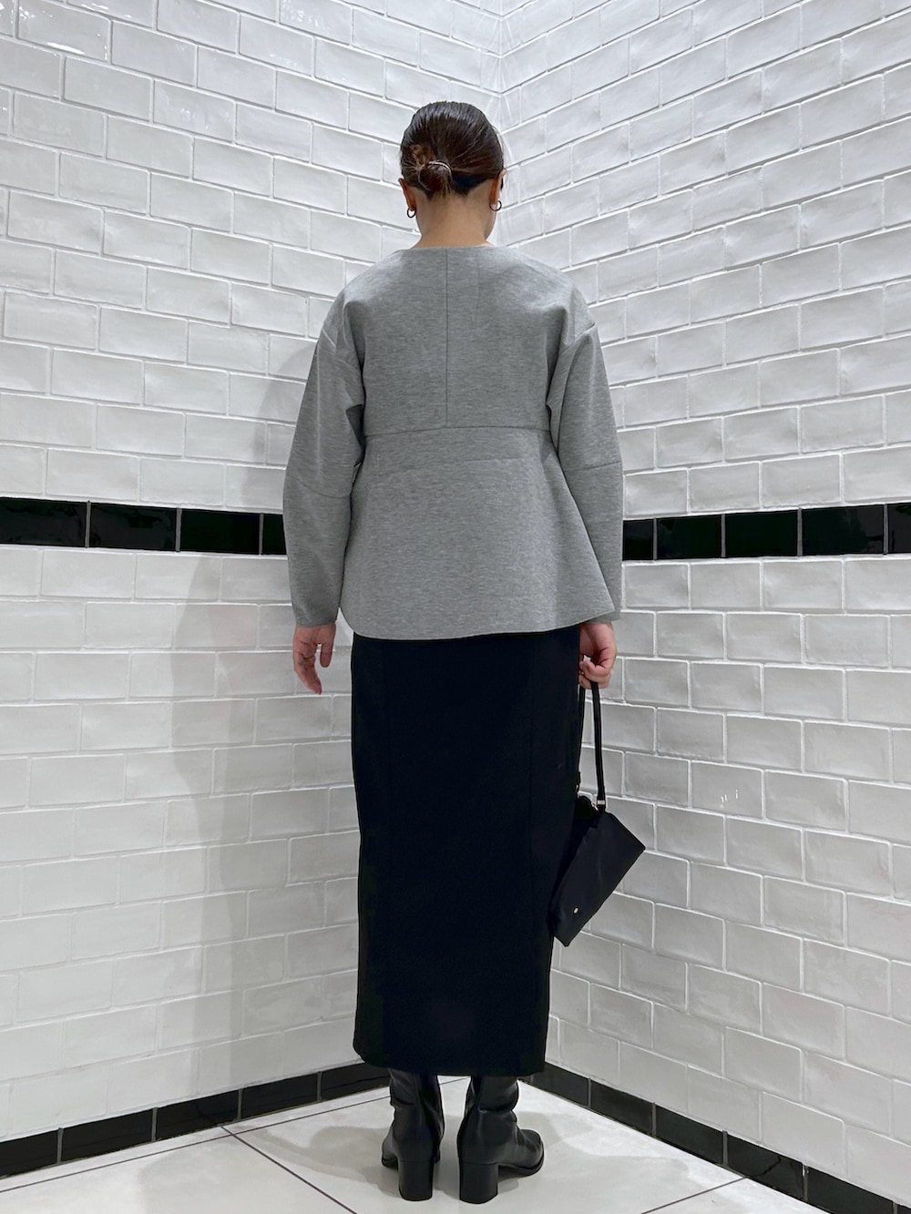 グレー系のワンピース、ブラック系のブーツ、ブラック系のハンドバッグを着用したレディースの秋コーディネートの2枚目の写真