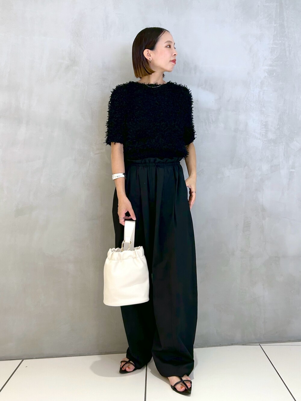 ブラック系のその他パンツ、ブラック系のニット/セーター、ホワイト系のショルダーバッグを着用したレディースの夏コーディネートの4枚目の写真