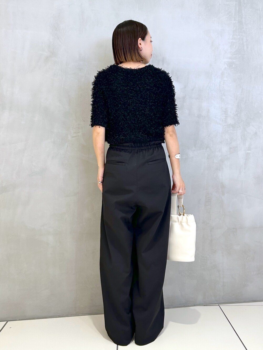 ブラック系のその他パンツ、ブラック系のニット/セーター、ホワイト系のショルダーバッグを着用したレディースの夏コーディネートの2枚目の写真