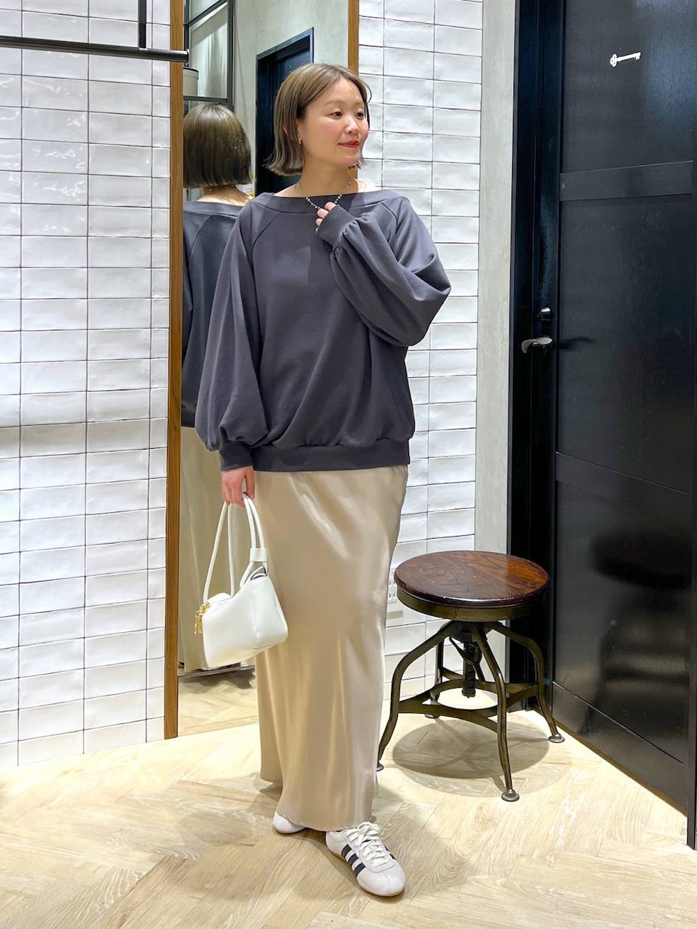 ベージュ系のスカート、ホワイト系のスニーカー、ホワイト系のショルダーバッグを着用したレディースの冬コーディネートの5枚目の写真