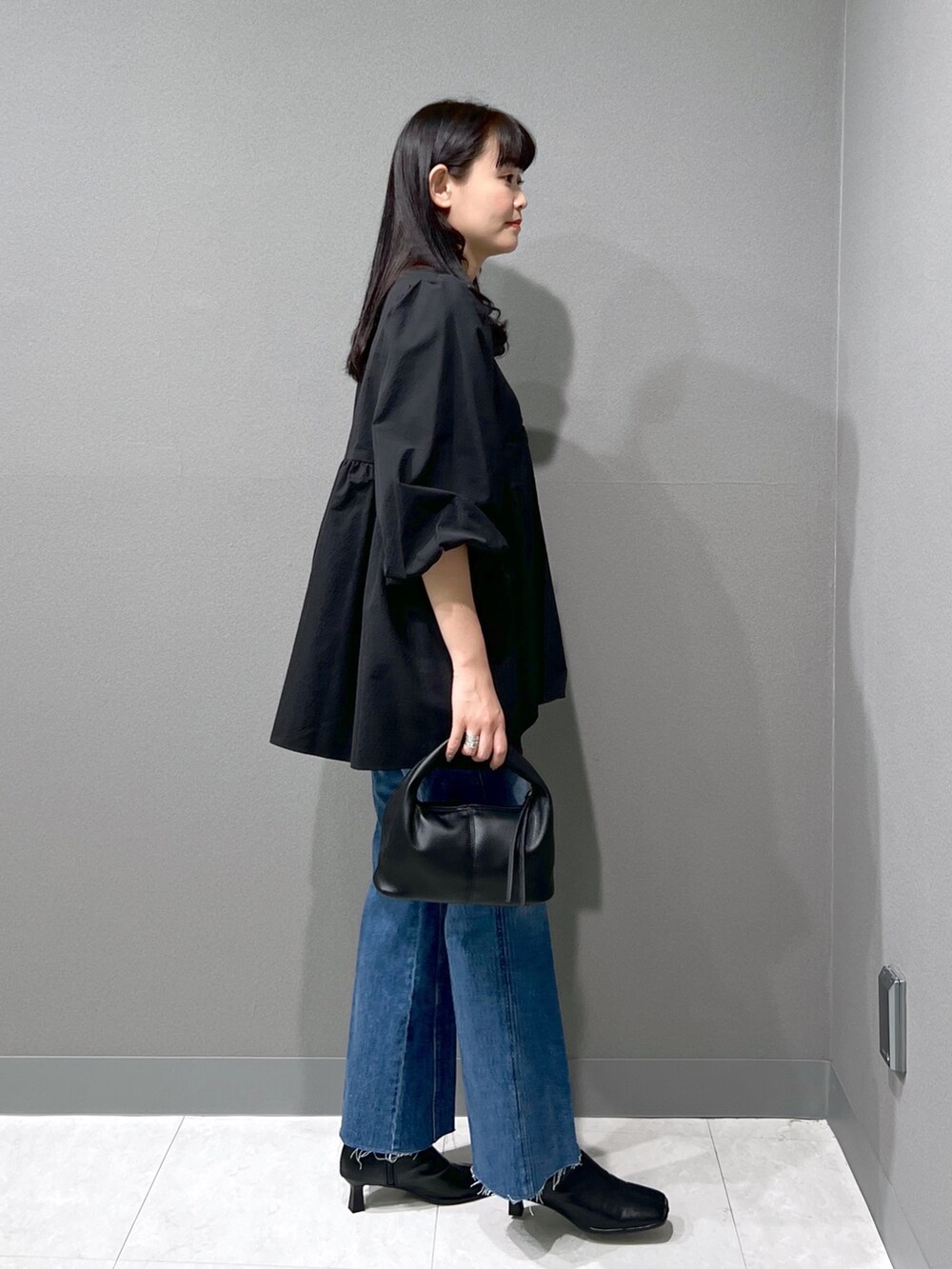 ブラック系のシャツ/ブラウス、ブルー系のデニムパンツ、ブラック系のハンドバッグを着用したレディースの秋コーディネートの2枚目の写真