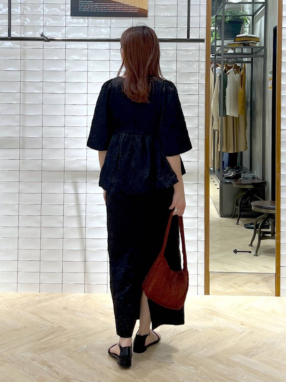 ブラウン系のハンドバッグ、ブラック系のサンダル、ブラック系のワンピースを着用したレディースの夏コーディネートの5枚目の写真