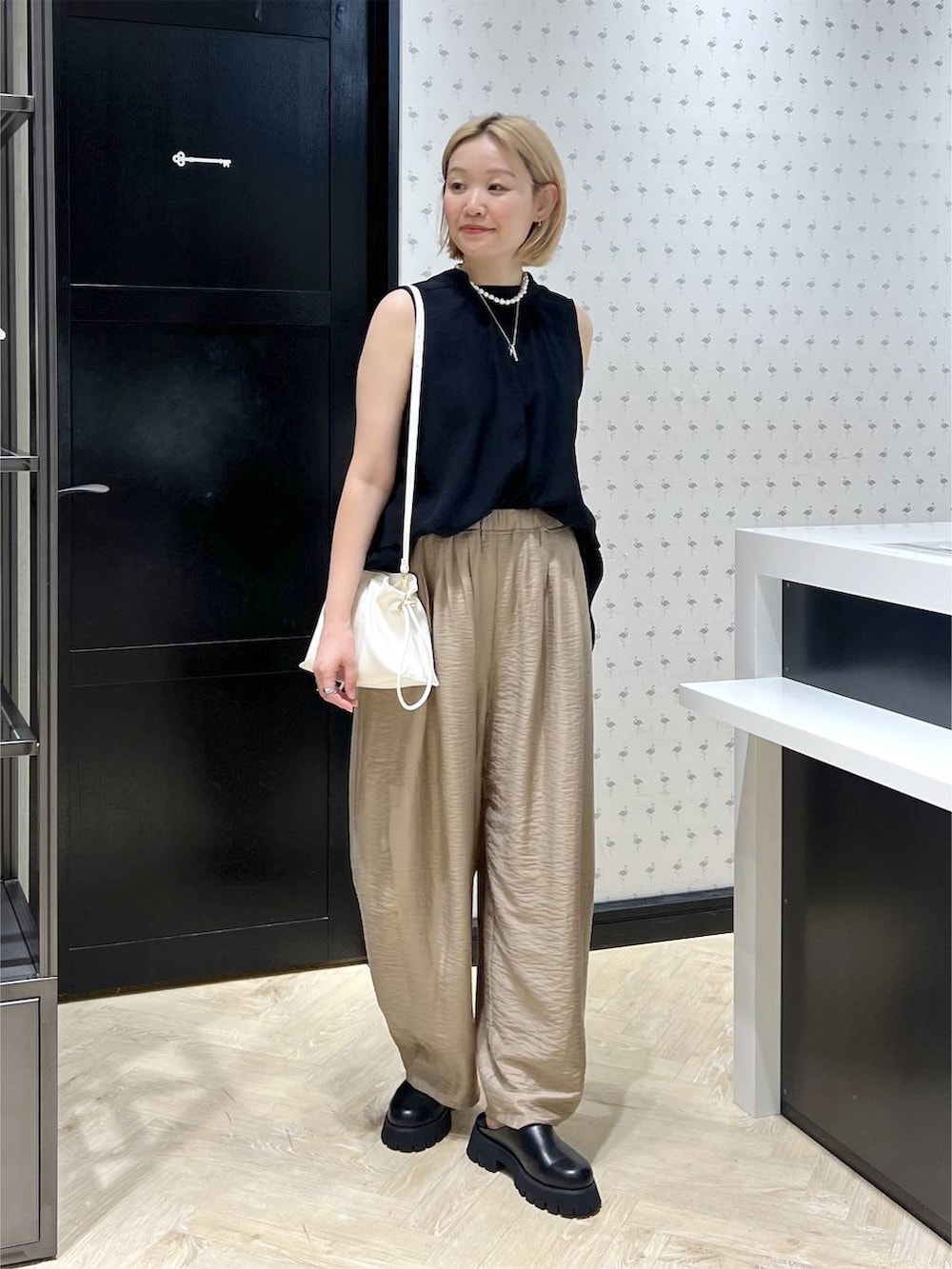 ホワイト系のショルダーバッグ、ブラック系のスリッポン、ベージュ系のその他パンツを着用したレディースの夏コーディネートの2枚目の写真