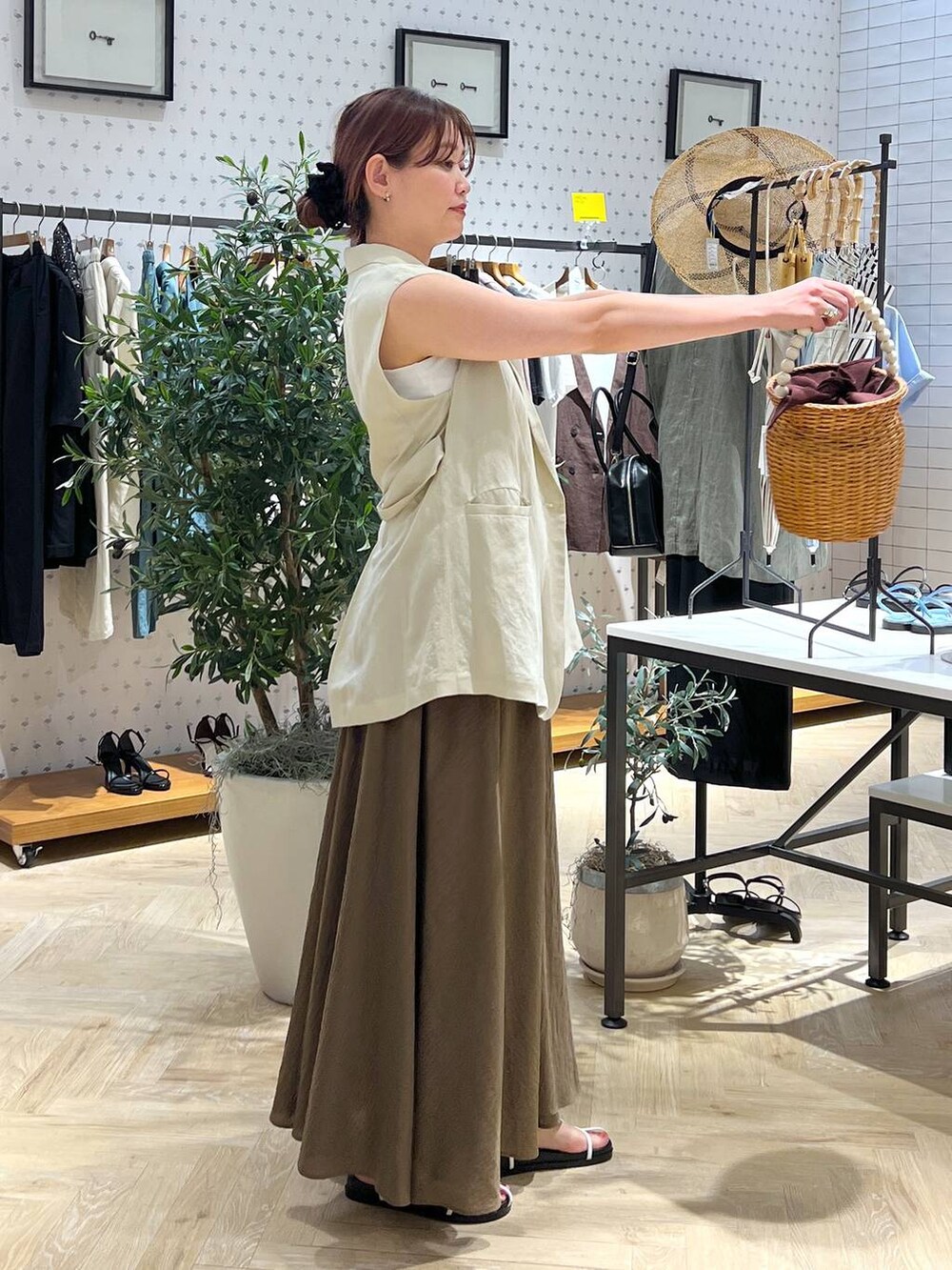 ブラウン系のかごバッグ、ホワイト系のキャミソール、ベージュ系のベストを着用したレディースの夏コーディネートの3枚目の写真