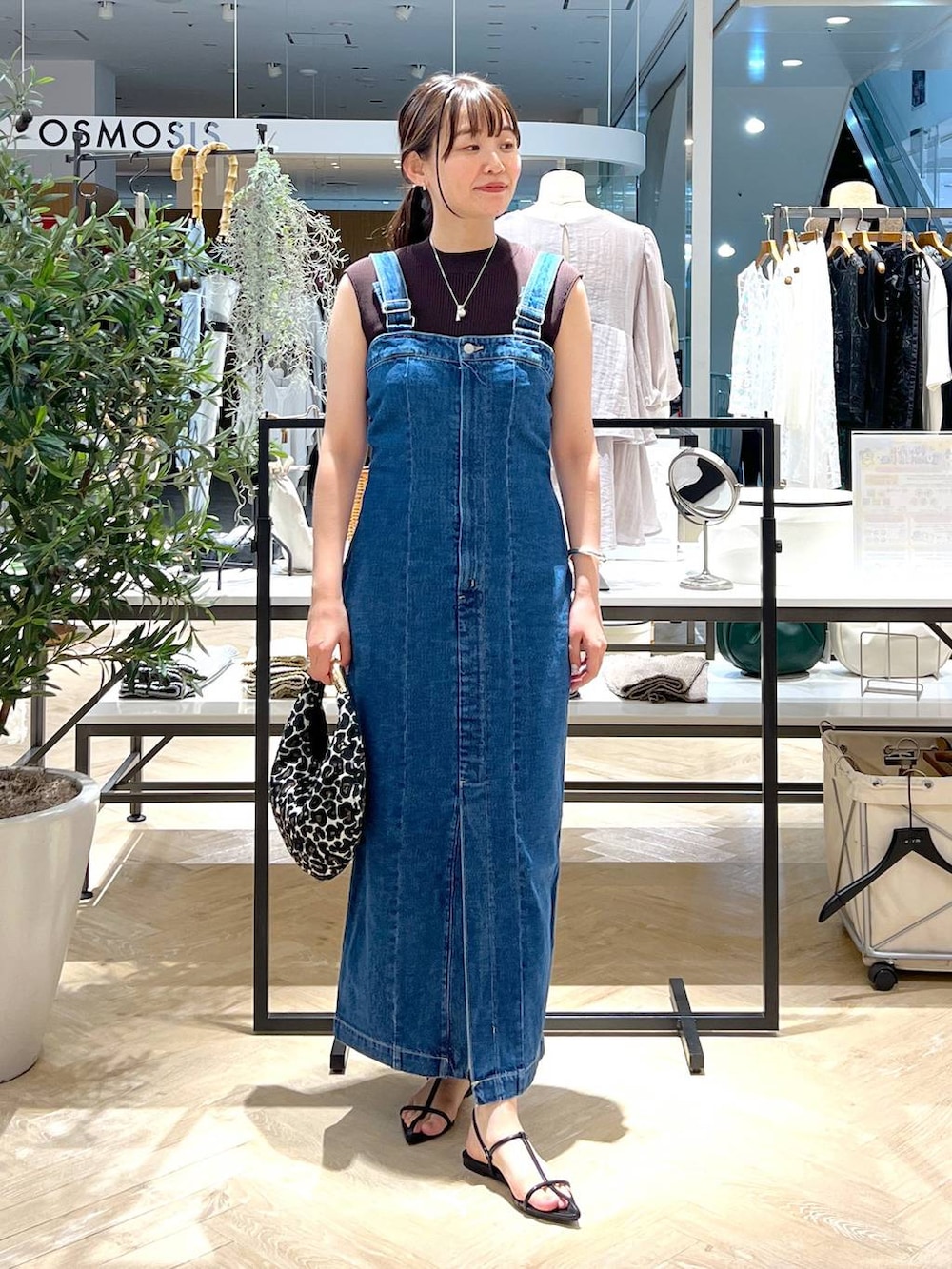 ブルー系のジャンパースカート、ブラック系のサンダル、ブラウン系のニット/セーターを着用したレディースの夏コーディネートの2枚目の写真