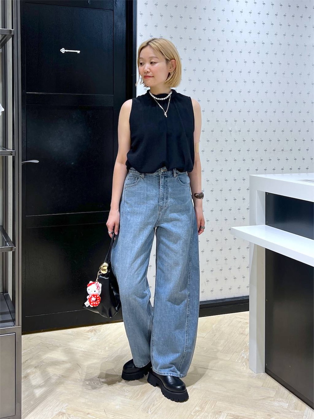 ブラック系のスリッポン、ブルー系のデニムパンツ、ブラック系のショルダーバッグを着用したレディースの夏コーディネートの2枚目の写真