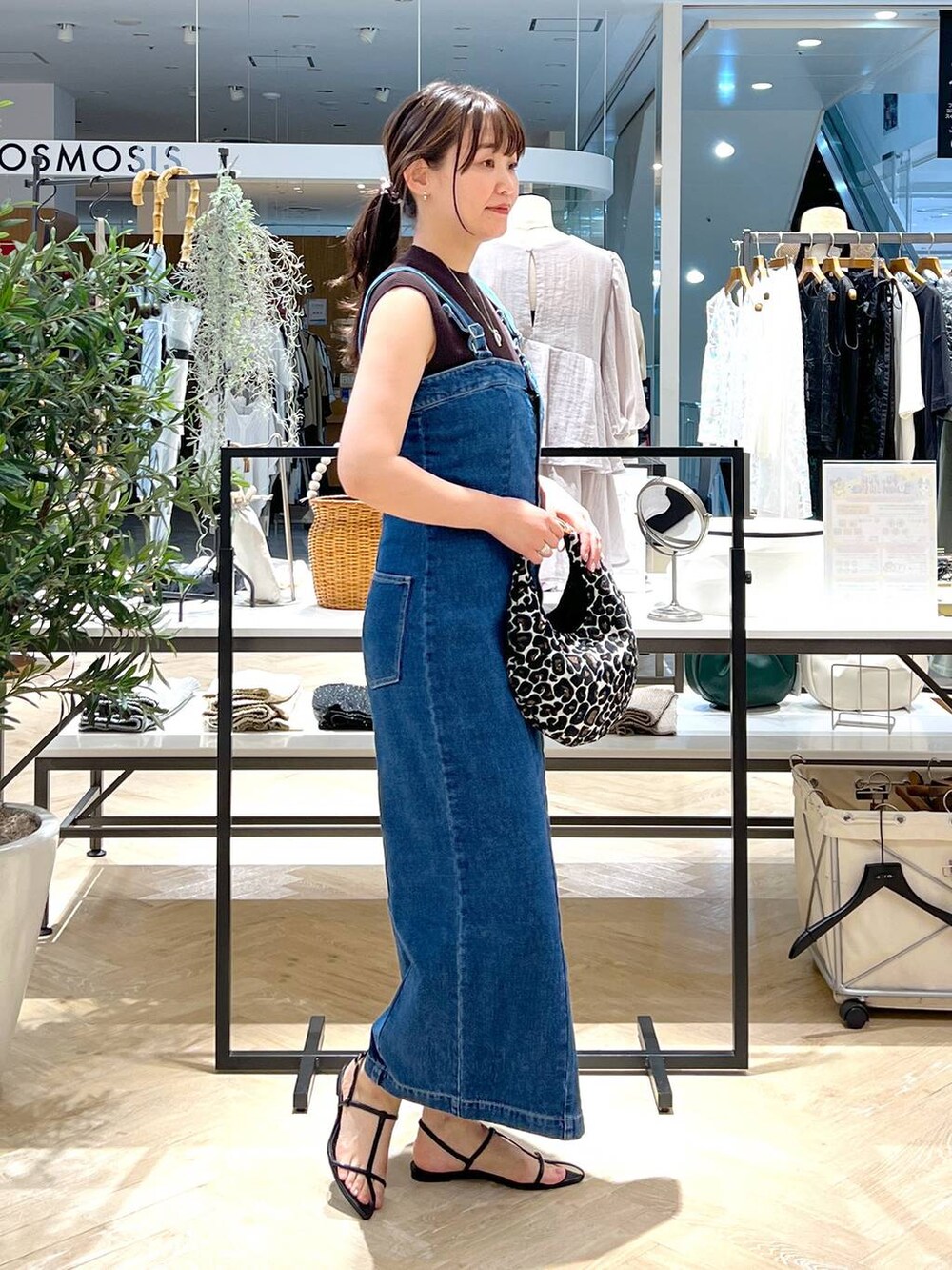 ブルー系のジャンパースカート、ブラック系のサンダル、ブラウン系のニット/セーターを着用したレディースの夏コーディネートの3枚目の写真