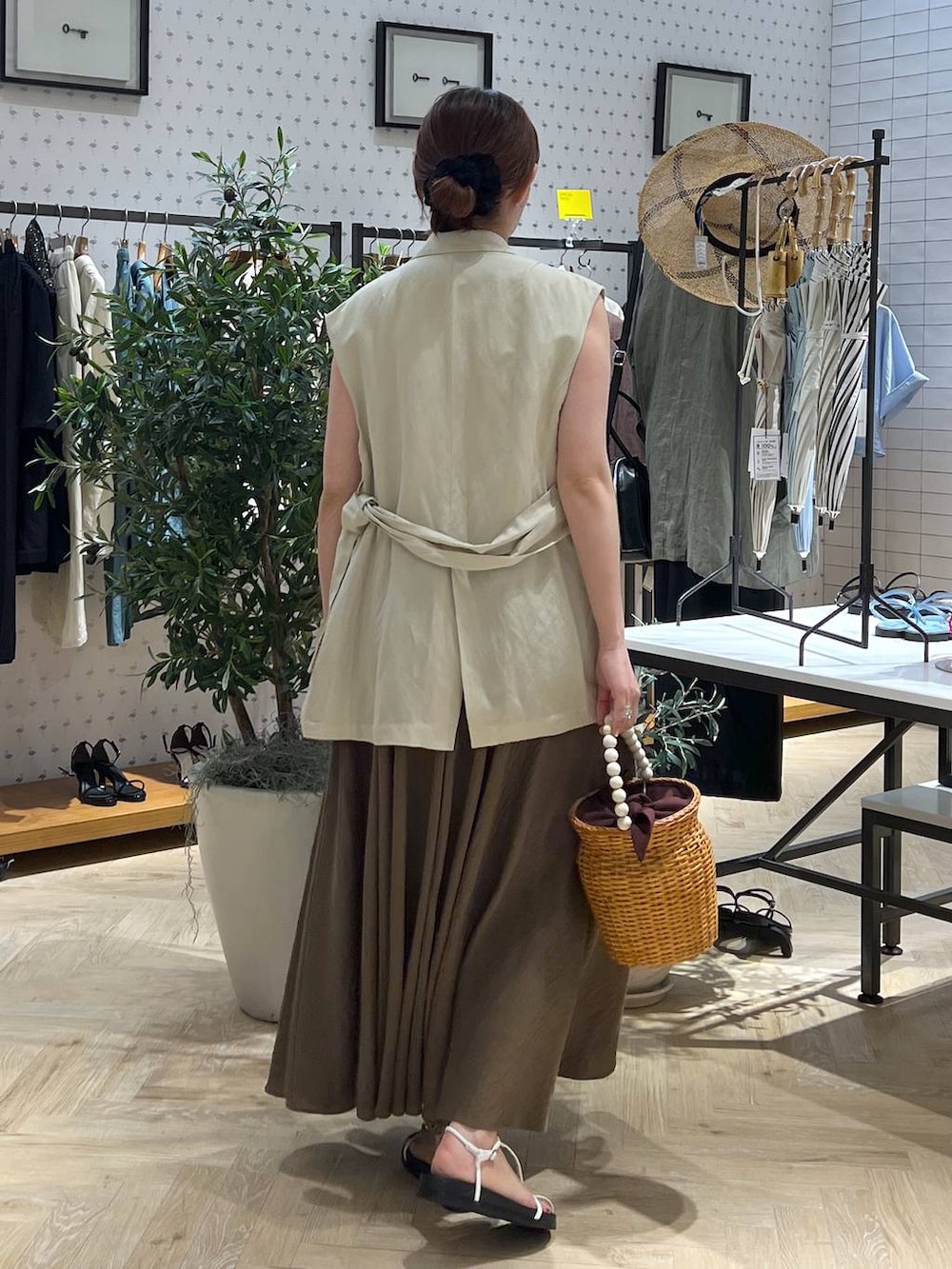 ブラウン系のかごバッグ、ホワイト系のキャミソール、ベージュ系のベストを着用したレディースの夏コーディネートの5枚目の写真